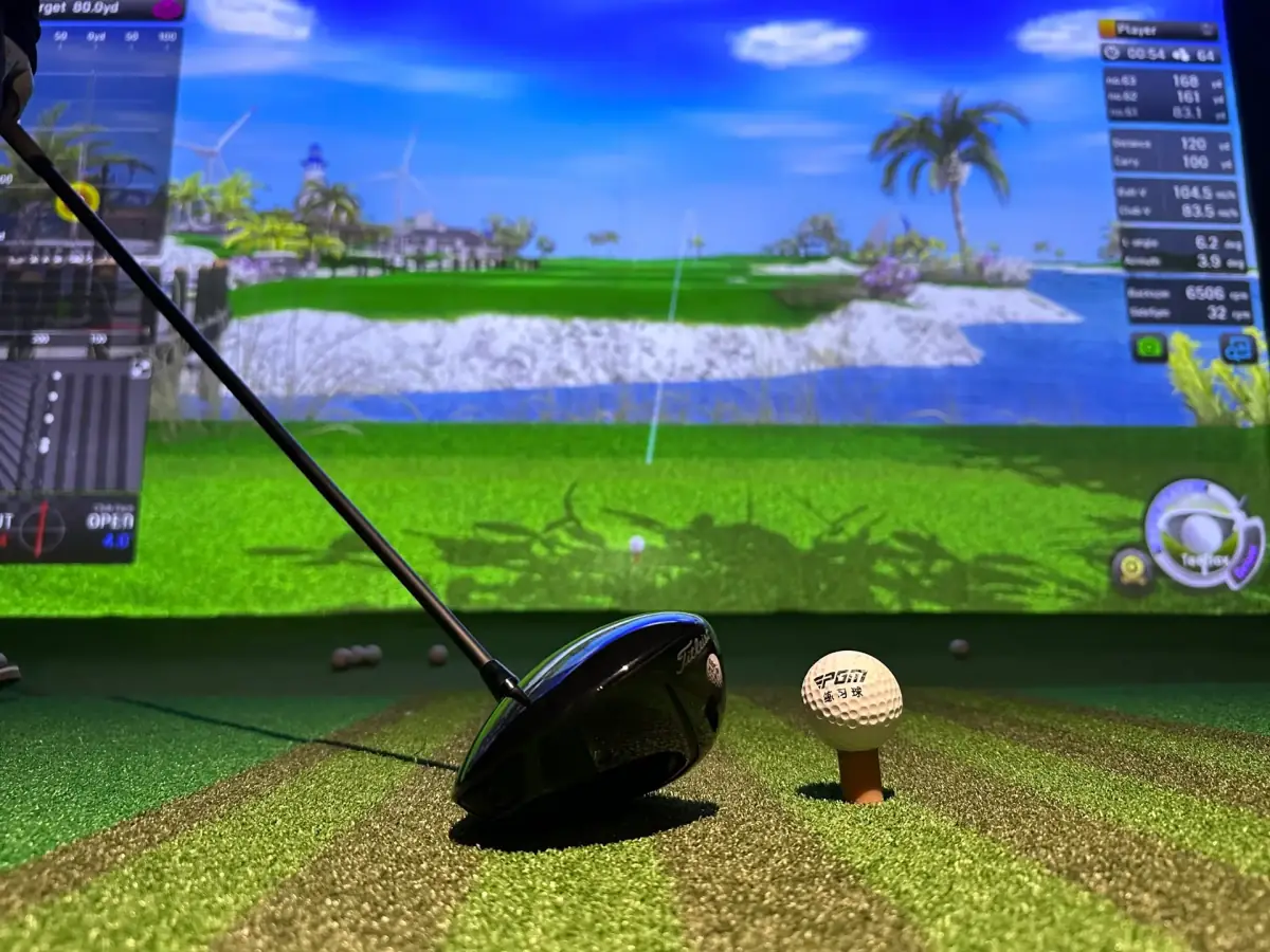 A driver behind a ball on a tee, with a course and shot data on the simulator screen at PGM Indoor Golf Calgary