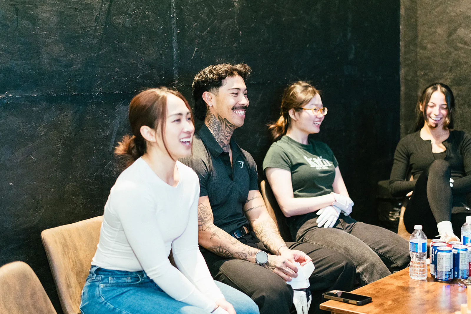 Four friends laugh together on the seating beside a PGM simulator bay
