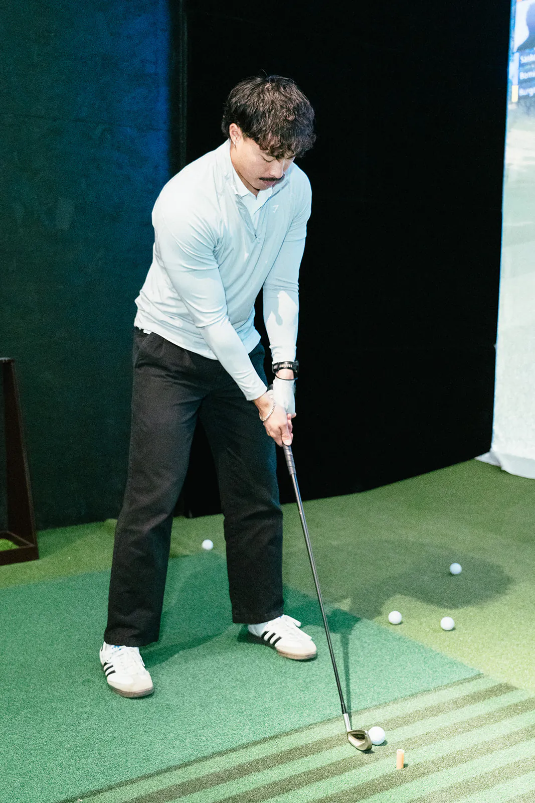 A golfer at the top of his backswing in front of the simulator screen