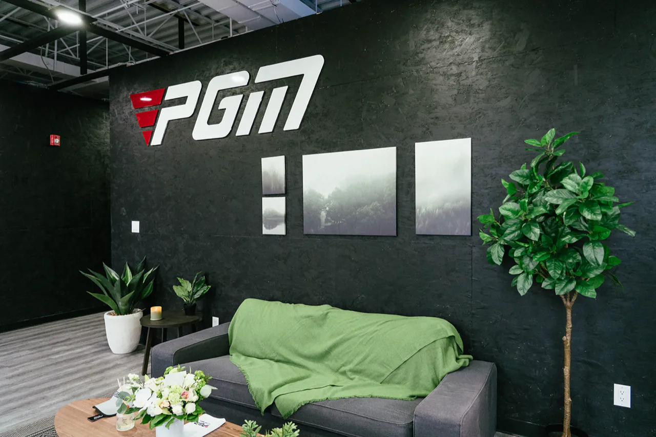 The PGM lounge, with a sofa and plants under the PGM logo wall
